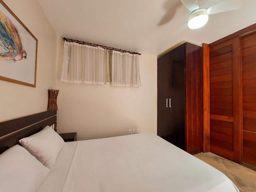 Quarto no Concha Tropical Flat. A cama está à esquerda, e à sua frente há um guarda-roupa. Há uma janela do lado da cama, na parede no centro da foto. Representa o post sobre airbnb em Itacaré.