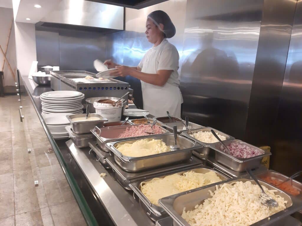 Cozinheira fazendo tapioca na chapa no Ritz, com os utensílios e ingredientes necessários ao lado