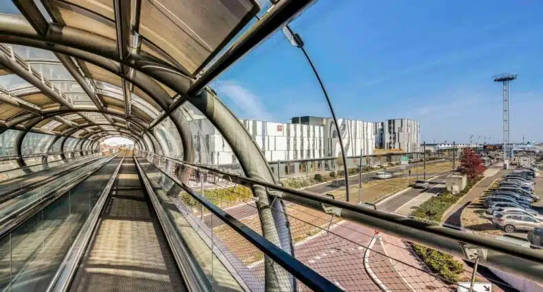 Visão do ibis Paris Coeur d'Orly Airport, um dos hotéis perto do Aeroporto de Orly, na passarela do local. A parte esquerda da imagem mostra a extensão da ponte do aeroporto, enquanto no lado direito pode-se ver o prédio do hotel ao longe.