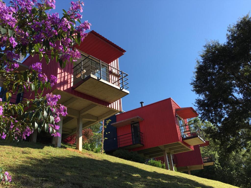 Parte do Latitude Lodge que mostra cada estúdio em formato de container suspenso por pilastras de concreto. Em volta tem bastante árvores e plantas, imagem ilustrando post Airbnb em Cunha.