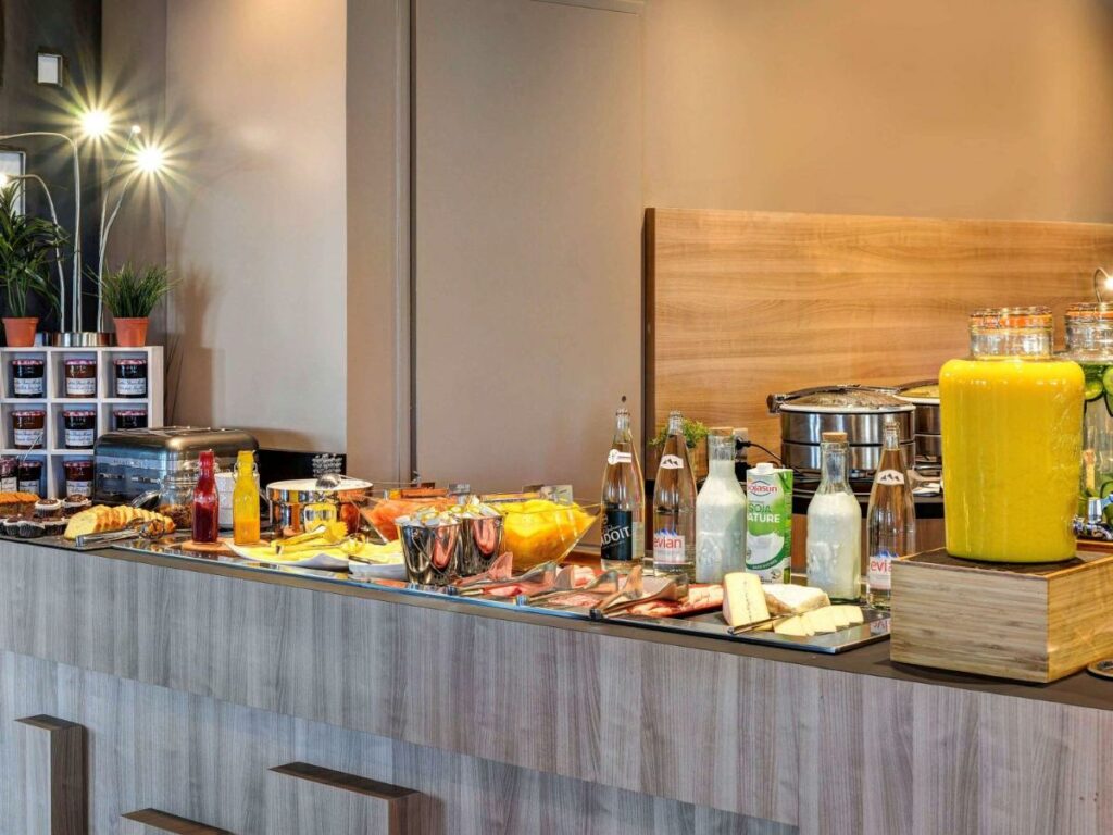 Bancada de café da manhã do Novotel Paris 14 Porte d'Orléans com várias opções de alimentos e bebidas.