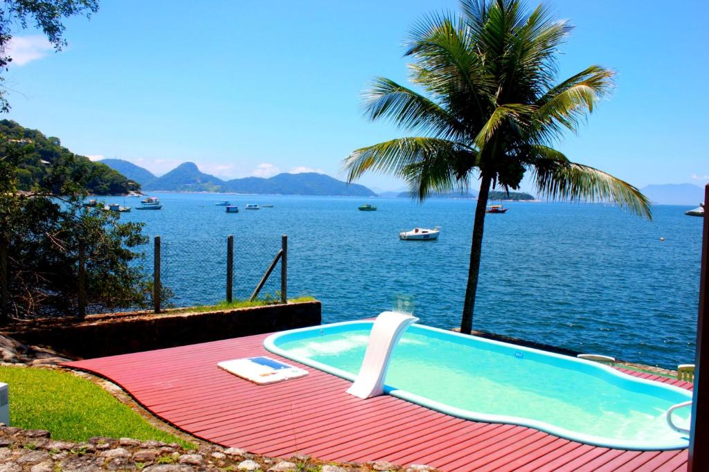 Área externa do Ocean Green Flats. No lado direito está a piscina da hospedagem e ao fundo o mar. Imagem para ilustrar o post airbnb em Angra dos Reis.