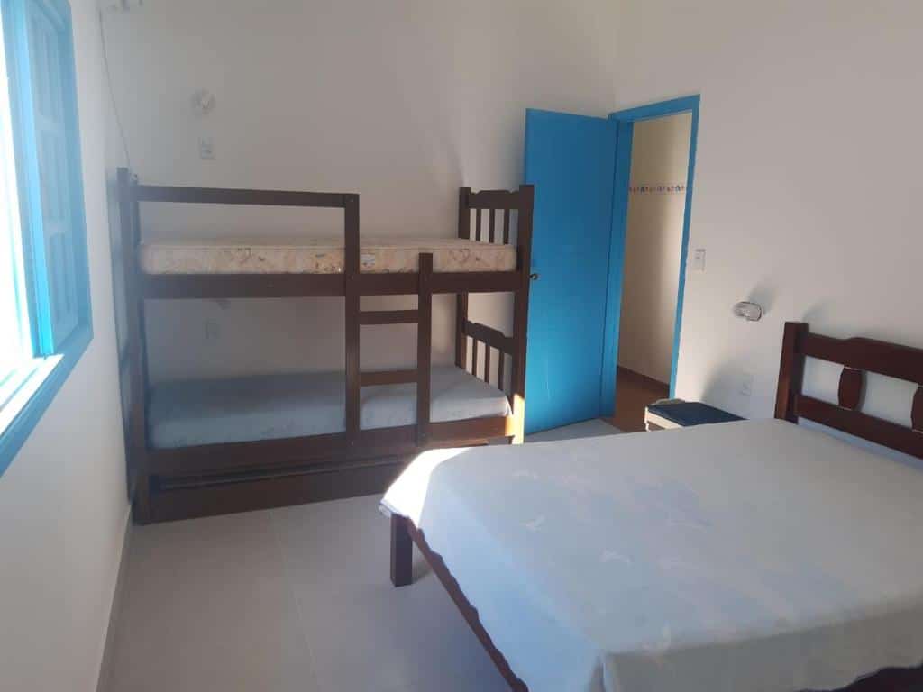 Quarto do Pé na Areia - Casa para temporada, um dos airbnb em Barequeçaba. Uma cama de casal está encostada na parede ao lado direito e encara uma janela. Ao lado esquerdo da cama há uma beliche.