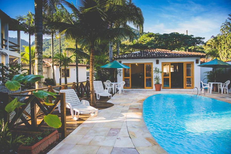 Área de lazer da Pousada Casarão com piscina do lado direito da imagem, do lado esquerdo cadeiras e ao fundo a estadia.