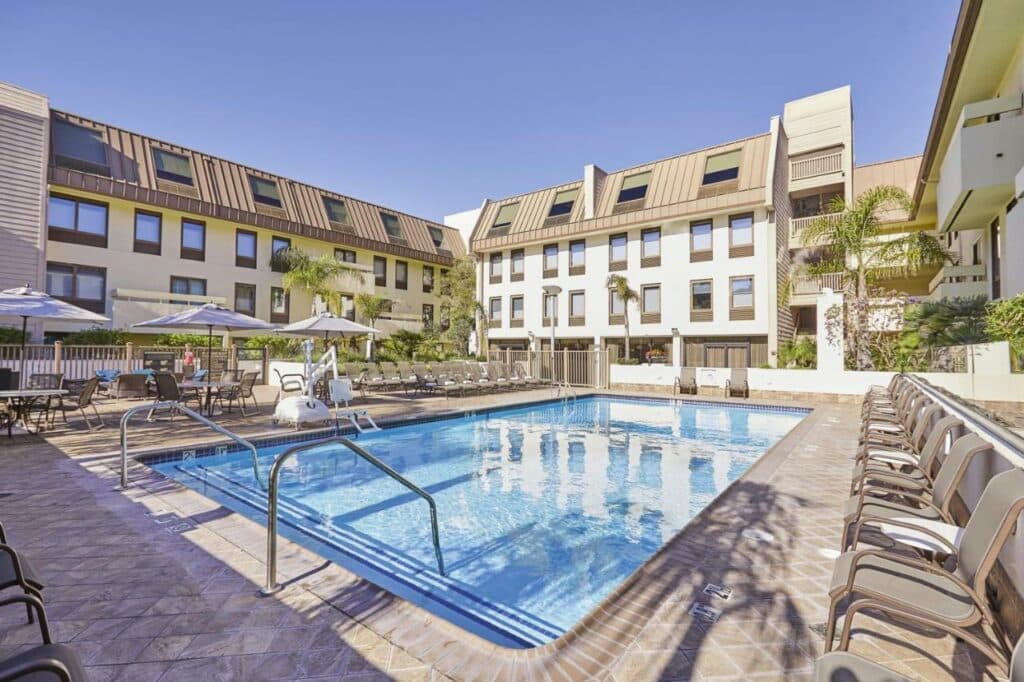 Piscina do ar livre do Riu Plaza Fisherman’s Wharf com piscina no centro da imagem e do lado direito e esquerdo da piscina cadeiras.