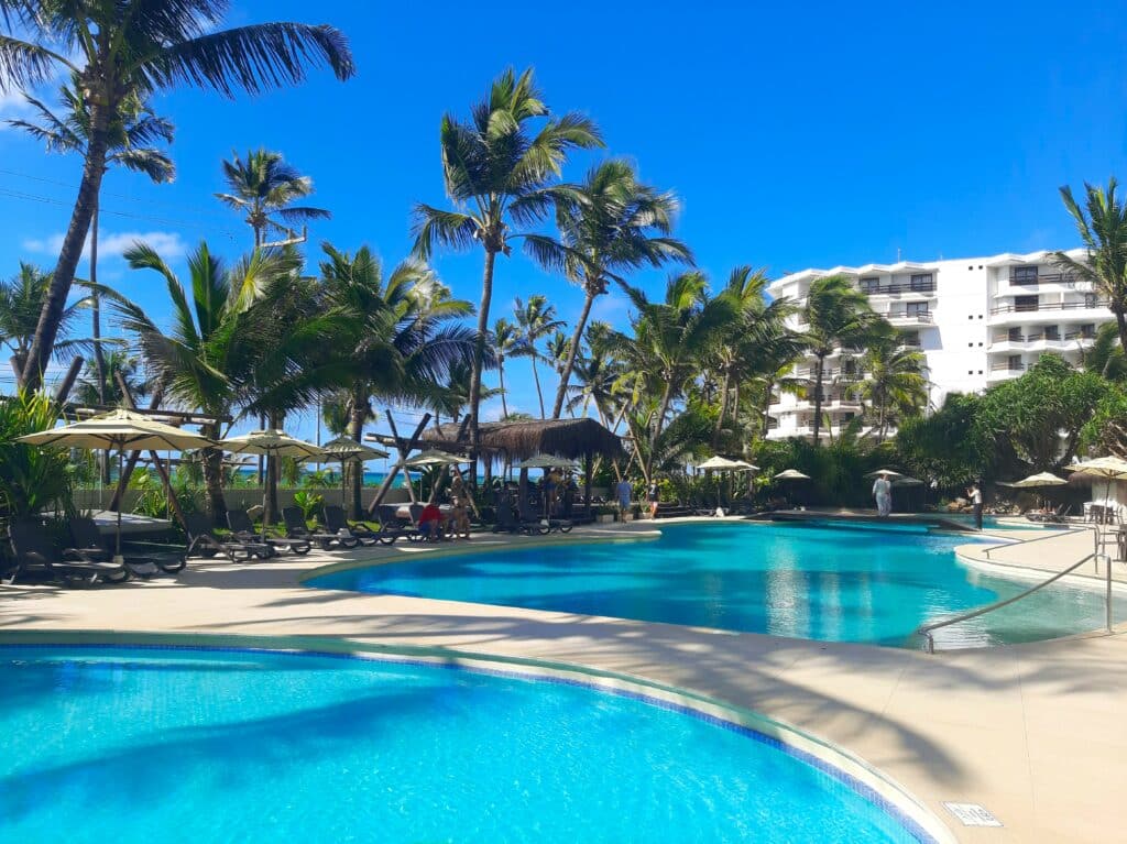 Piscinas do Ritz Lagoa da Anta com coqueiros em volta, espreguiçadeiras e guarda-sóis