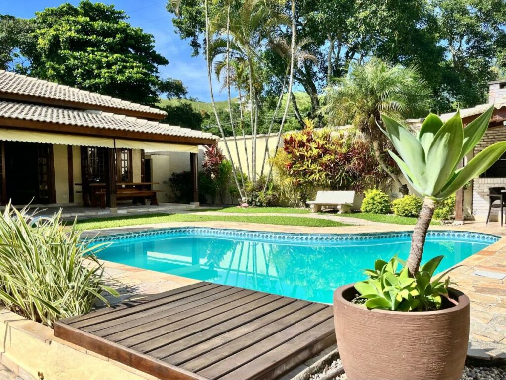 Piscina ao ar livre da Casa de temporada estilo rústico durante o dia com a piscina a frente e do lado esquerdo a propriedade. Representa airbnb na praia da Juréia.
