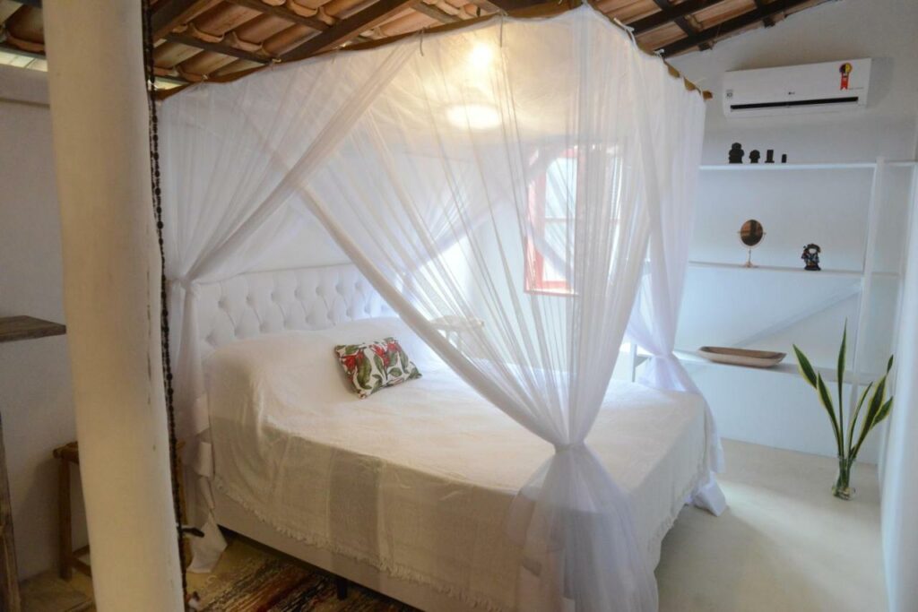 Quarto da Casa Alegre Trancoso, piscina, 3 suítes e ar-cond com cama de casal do lado esquerdo da imagem. Representa airbnb em Trancoso.
