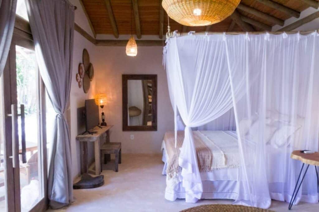 Quarto da Casa da Luz – Vila Serena, Trancoso com uma cama de casal do lado direito da imagem e em frente a cama uma cômoda com TV. Representa airbnb em Trancoso.
