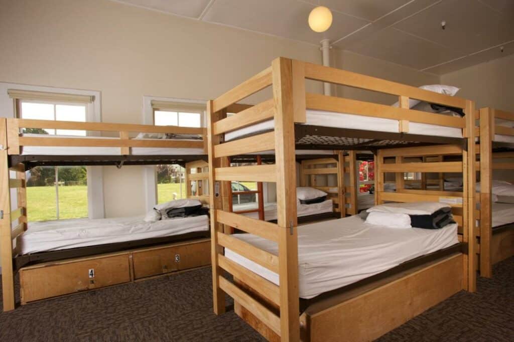 Quarto compartilhado do HI San Francisco Downtown Hostel com duas beliches a frente e ao fundo mais três beliches. Representa hotéis em San Francisco.