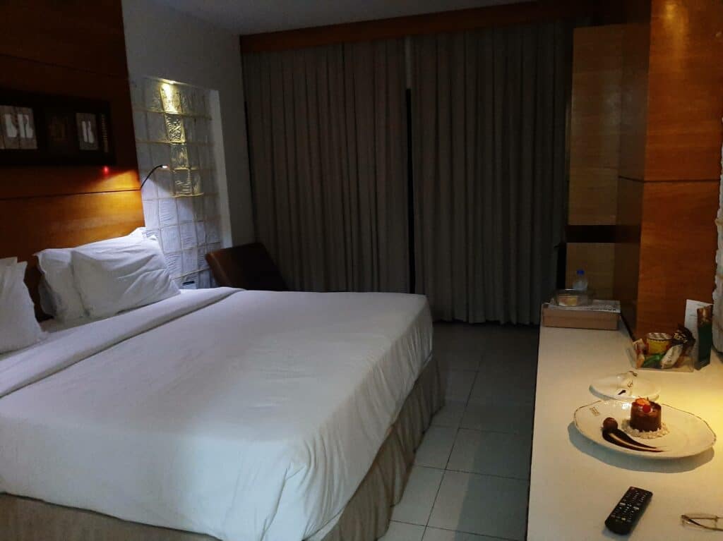 Quarto Design Floor Luxo do Ritz Lagoa da Anta, com cama de casal, uma iluminação mais escura e um balcão com controle e um prato com doce em cima