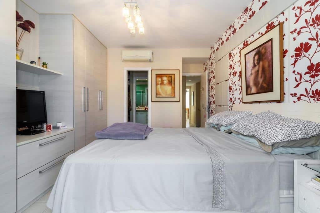 Quarto do Linda Casa c piscina churrasq Barra da TijucaRJ com cama de casal do lado direito da cama e em frente a cama uma cômoda com TV e um guarda-roupa. Representa airbnb na Barra da Tijuca.
