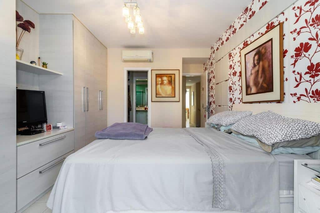 Quarto do Linda Casa c piscina churrasq Barra da TijucaRJ com cama de casal do lado direito da cama e em frente a cama uma cômoda com TV e um guarda-roupa. Representa airbnb na Barra da Tijuca.