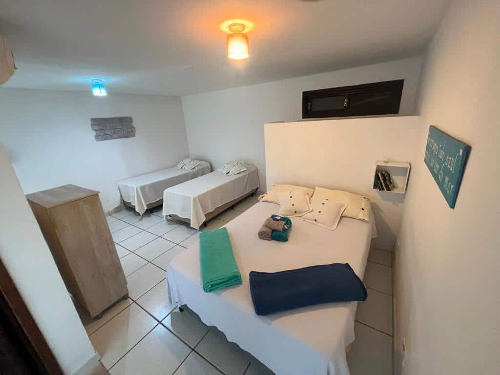 Quarto familiar do Loft com vista ao mar com cama de casal do lado direito da imagem e do lado esquerdo duas camas de solteiro. Representa airbnb na praia de Calhetas.