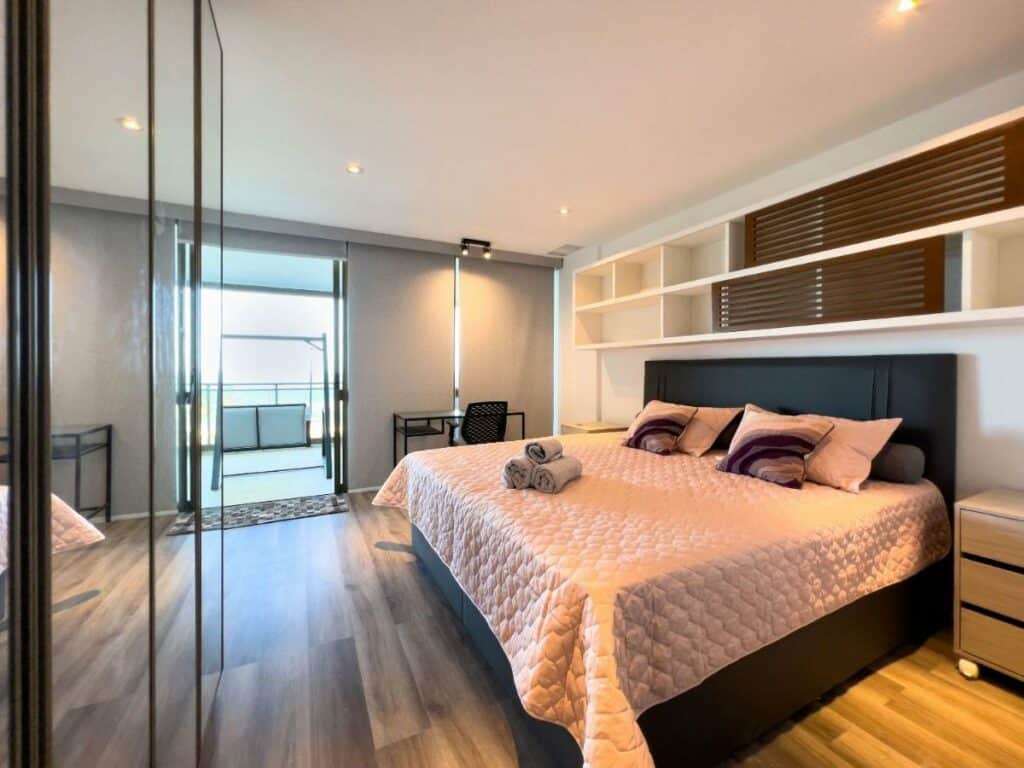 Quarto do Luxo e Vista Mar Maravilhosa na Barra da Tijuca B11-0013 com cama de casal do lado direito da imagem com uma cômoda em cada lado da cama e do lado esquerdo da cama uma mesa com cadeira. Representa airbnb na Barra da Tijuca.
