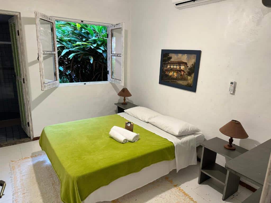 Quarto do Vila dos Tangarás, Casa 1 Praia, a 30m do mar com cama de casal do lado direita da imagem com uma cômoda em cada lado da cama com luminária. Representa airbnb na praia de Calhetas.