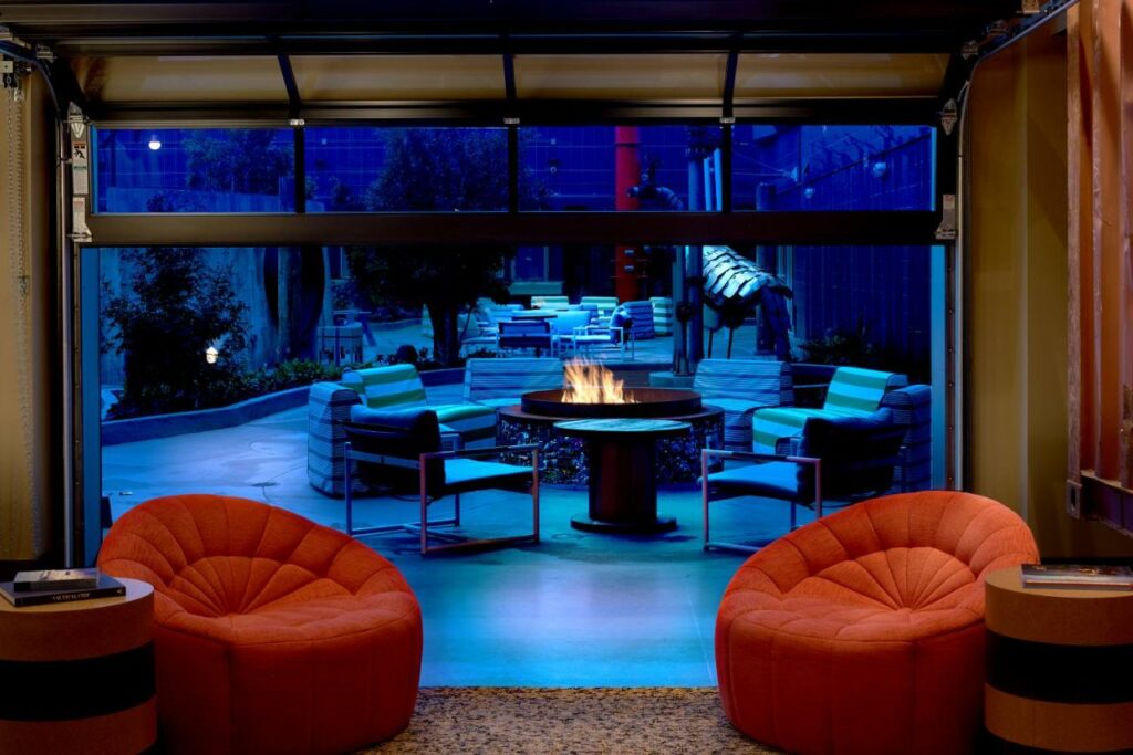 Sala de estar do Hotel Zephyr San Francisco com duas cadeiras a frente e ao fundo uma lareira na área de fora com cadeiras.