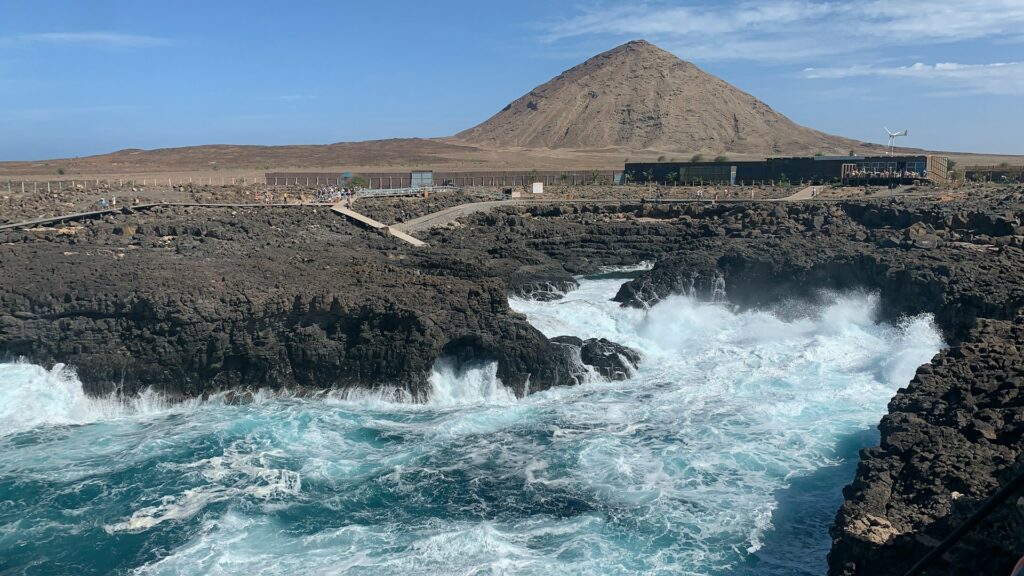 vista da Ilha de Sal com ondas fortes batendo em pedras altas e uma montanha bem pontuda ao fundo, em Cabo Verde para ilustrar o post de diferenças entre PB4 e seguro viagem