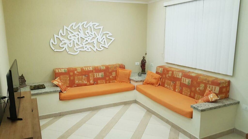 Sala de estar do Toque Toque Grande Paraiso com dois sofás a frente e do lado esquerdo uma cômoda com TV.