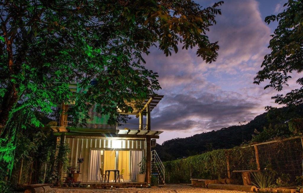 Fora do Loft Superior Villa Dallê. Um container com um loft em cima do outro, no térreo uma mesa com cadeiras, ao redor árvores.