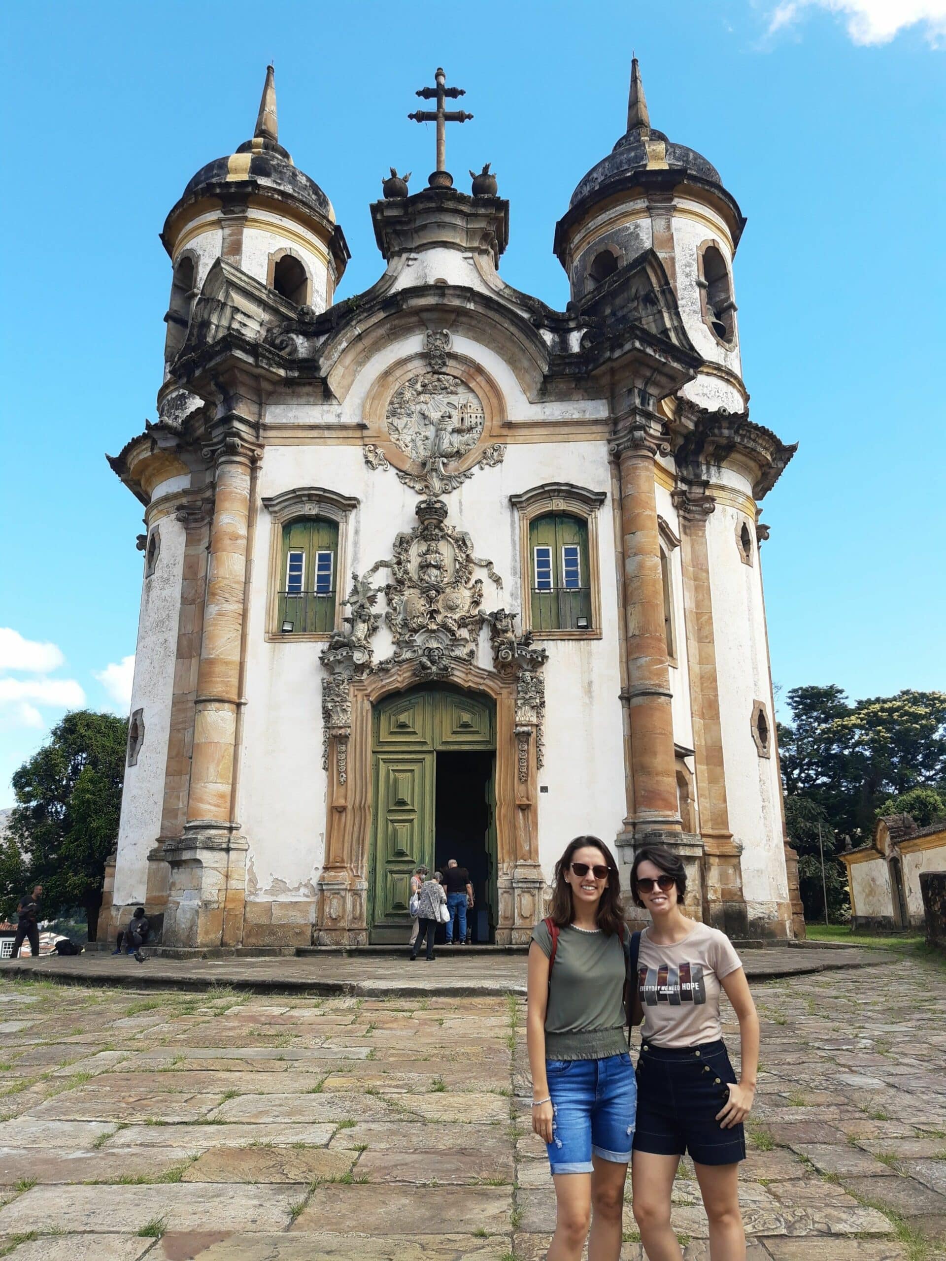 Duas mulheres adultas posando para uma foto em frente à Igreja São Francisco de Assis, em Ouro Preto.