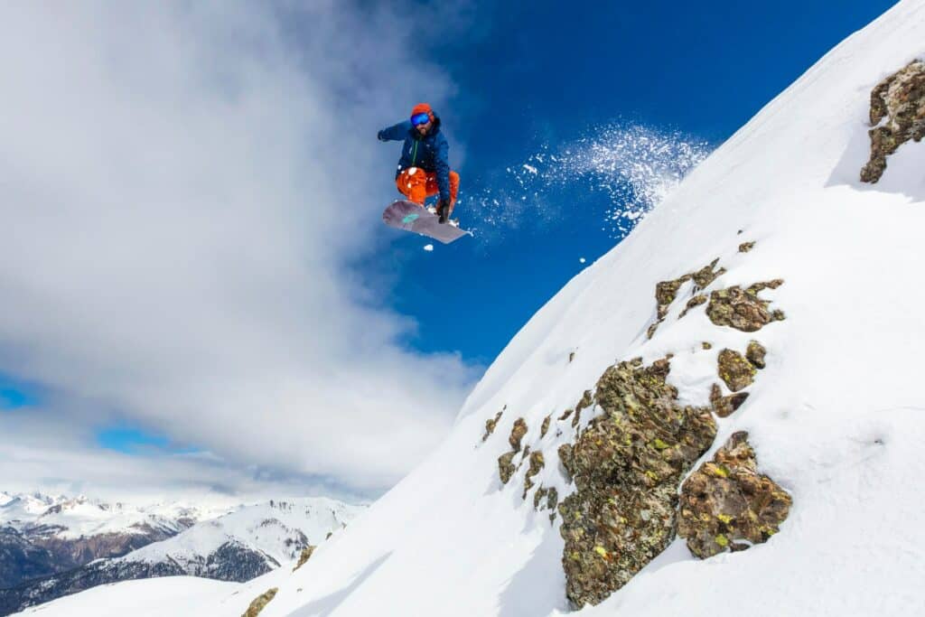 pessoa fazendo snowboard, saltando de uma montanha coberta de neve em Montgenevre, na França, para ilustrar o post de seguro viagem para esqui e snowboard