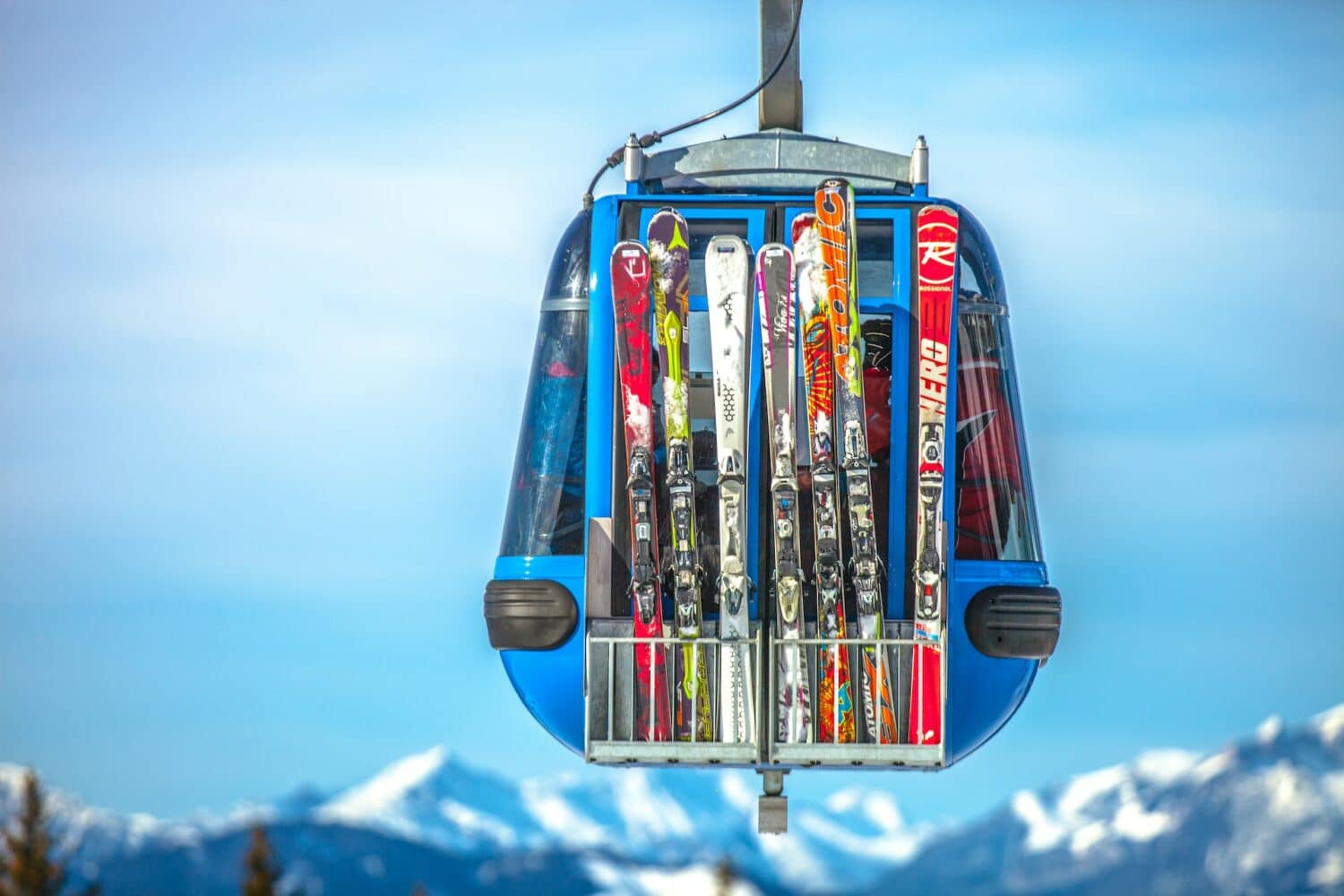 vista de um bondinho azul em Zell am Ziller, na Áustria, com várias pranchas de esqui coloridas e montanhas de neve ao fundo, para ilustrar o post de seguro viagem para esqui e snowboard
