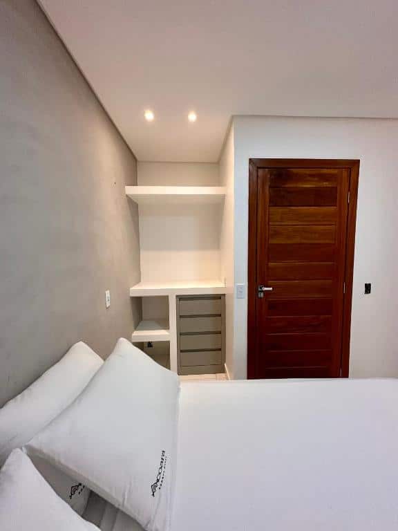 Foto do quarto do Acoara Beco Doce. Representa o post sobre airbnb em Jericoacoara. Vemos a cama de lado, e ao lado dela há uma porta e um armário feito com prateleiras e gavetas.