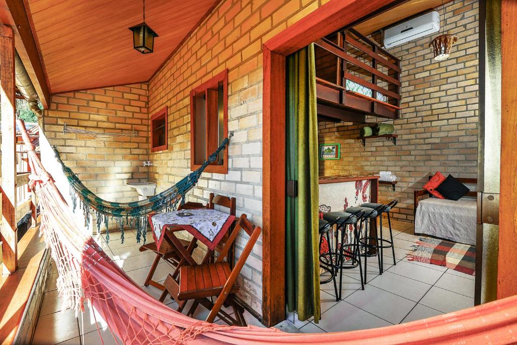 Área externa do airbnb Adora Suites. Na varanda do airbnb há uma mesa com duas cadeiras no lado direito, um tanque no lado esquerdo e duas redes, uma em cada ponta da varanda. A porta que dá acesso ao airbnb está no lado direito.