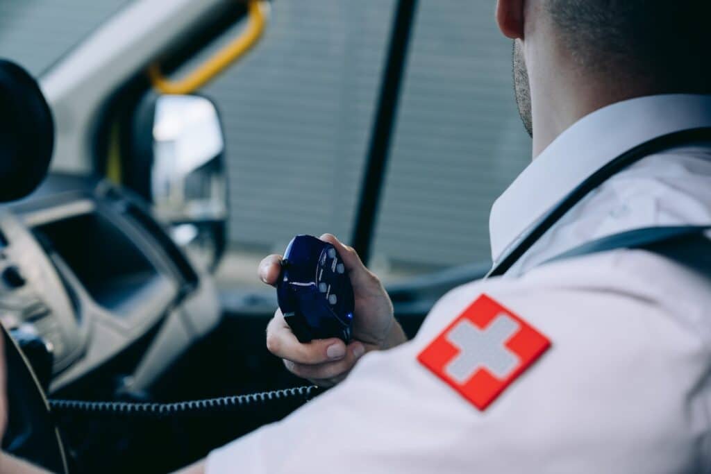 close num paramédico em uma ambulância segurando um pequeno microfone com uma mão