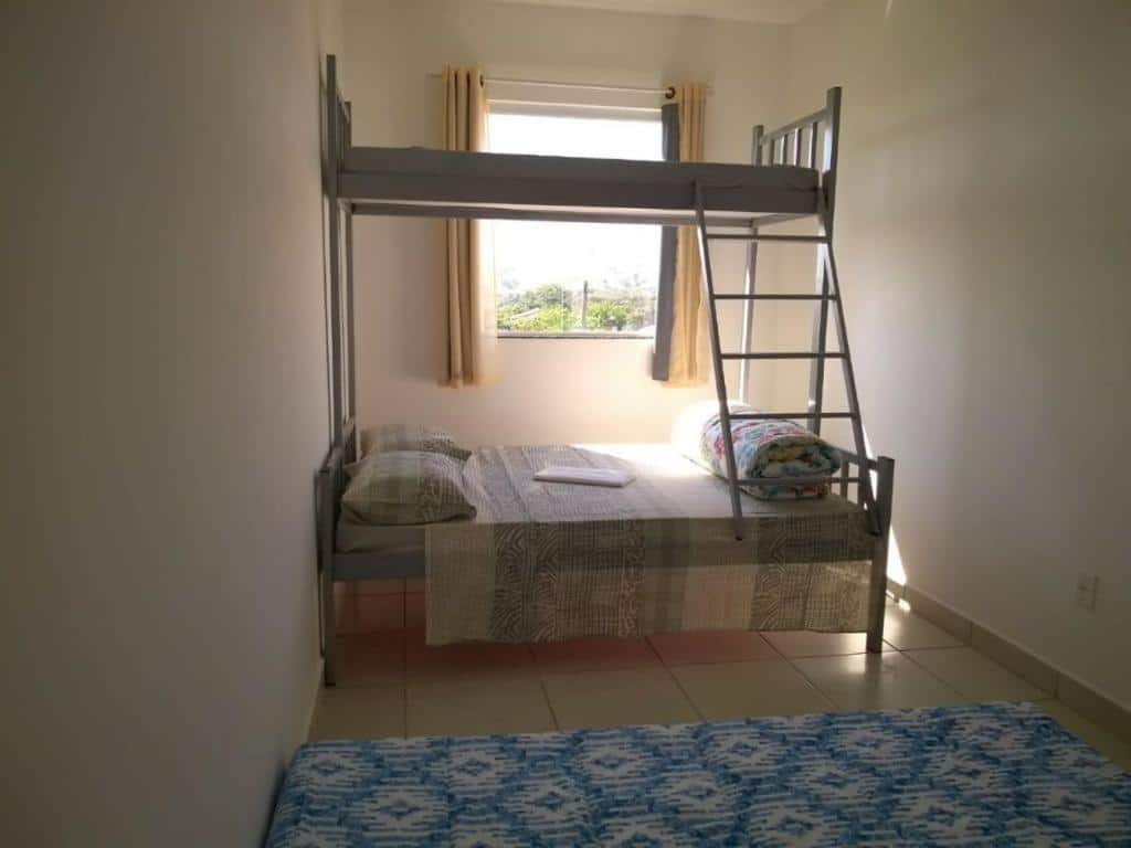 Quarto do airbnb Apartamentos Com Vista da Serra. No fundo do quarto há uma janela e uma beliche, já na frente é possível ver parte de um colchão de casal no chão. Imagem para ilustrar o post airbnb em Itatiaia.