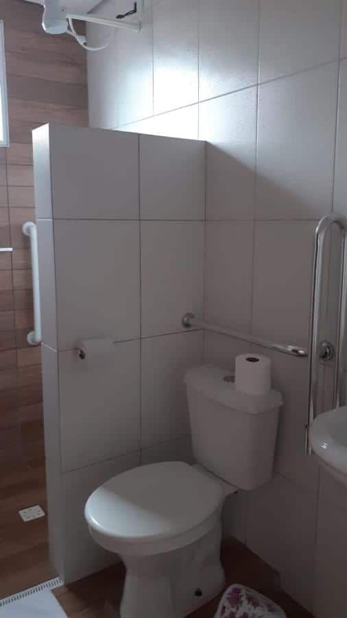 Banheiro com acessibilidade da Pousada Parapuã com vaso sanitário a frente com barras de apoio.