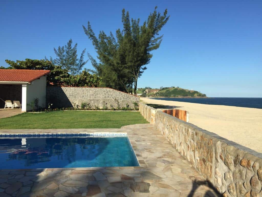 Área externa do Black Point Beach Club. Uma piscina do lado esquerdo, um muro no meio e do lado direito a praia.