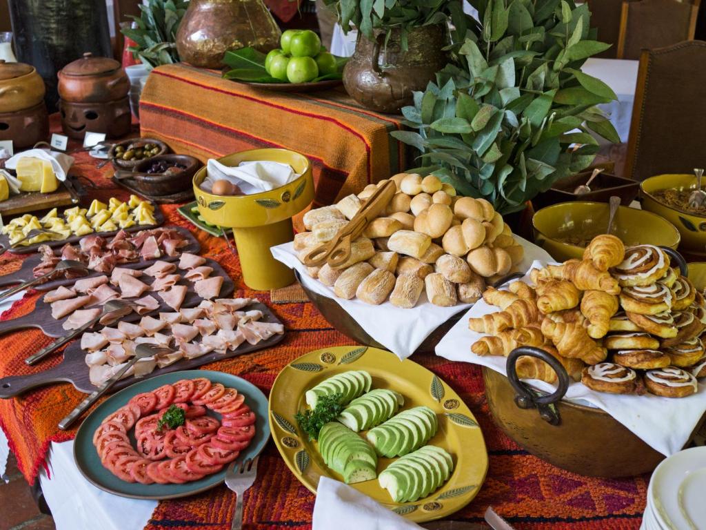 mesa de café da manhã do hotel inkaterra com vários pratos de pães, frutas, legumes e comidas típicas.