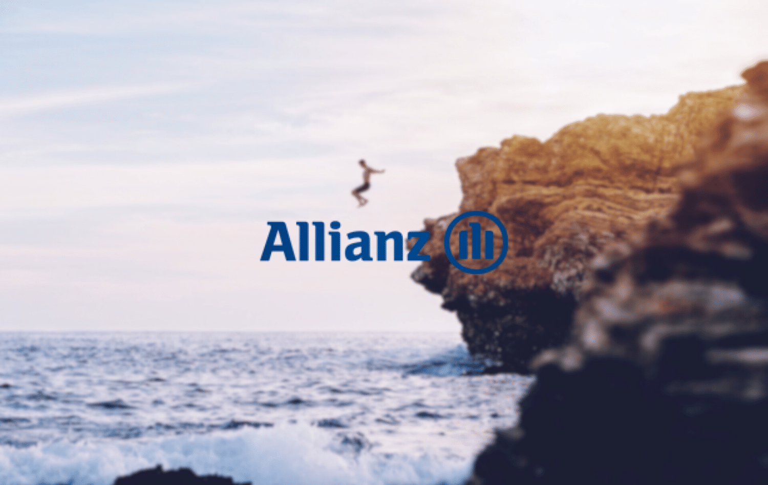 pessoa pulando de uma pedra com mar embaixo no Cameo Shores, em Corona del Mar, nos Estados Unidos, desfocado ao fundo com o logo da Allianz Seguro Viagem acima