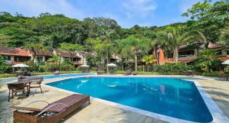 Vista da frente da piscina da Casa em Condomínio Pé na Areia na Praia do Engenho durante o dia com cadeiras do lado esquerdo da imagem e em frente a piscina. Representa airbnb na praia do Tenório.