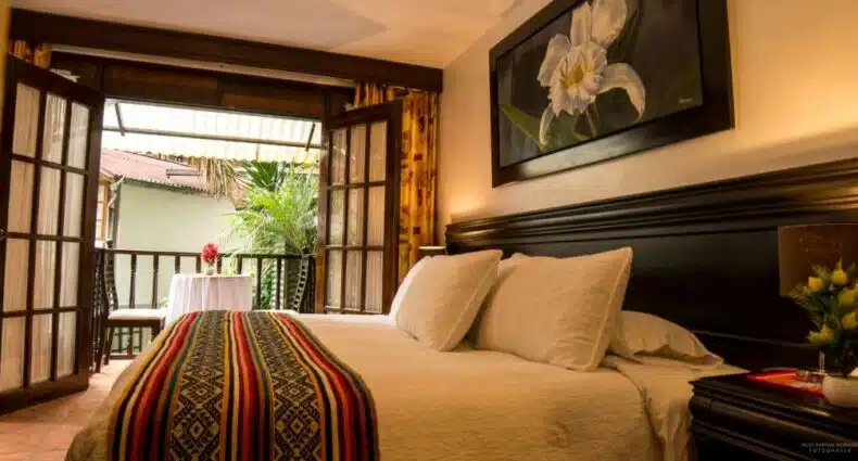 quarto do Gringo Bill's Boutique Hotel com uma cama de casal e uma varanda ao fundo com vista para o centro da cidade.