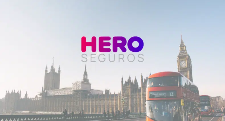 Cidade de Londres com o Palácio de Buckingham ao fundo, sob a imagem está o logo da marca Hero Seguros, para representar Hero Seguros