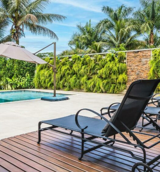 Imagem da piscina da Mansão de luxo perto da praia em Caraguatatuba durante o dia com cadeiras do lado direito da imagem e do lado esquerdo a piscina. Representa airbnb na praia de Tabatinga.