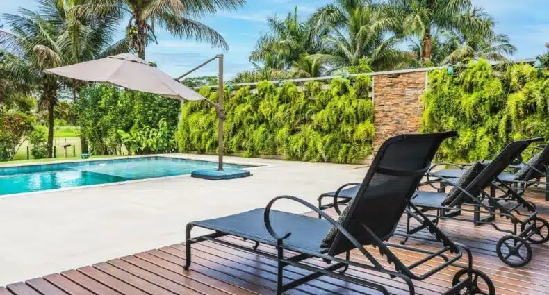 Imagem da piscina da Mansão de luxo perto da praia em Caraguatatuba durante o dia com cadeiras do lado direito da imagem e do lado esquerdo a piscina. Representa airbnb na praia de Tabatinga.