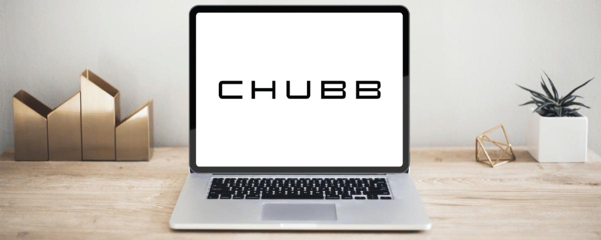 Um notebook aberto sob uma mesa de madeira, ele está na página inicial do site da seguradora Chubb, para representar seguro viagem Chubb