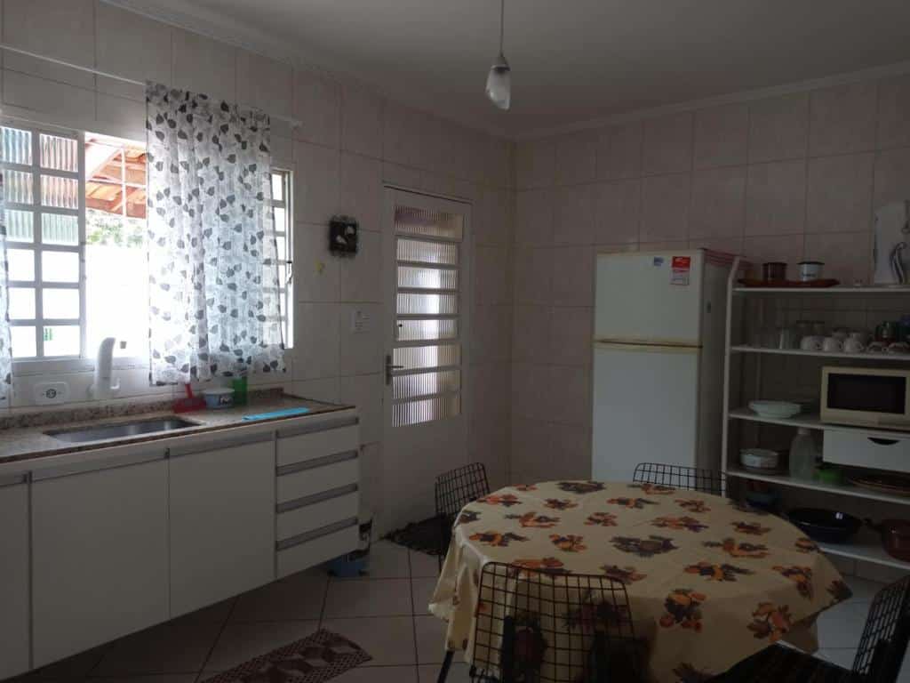Cozinha completa em Casa com linda Vista no Centro. No meio há uma mesa redonda com quatro cadeiras. A pia está na esquerda e a geladeira e outros utensílios estão na direita.
