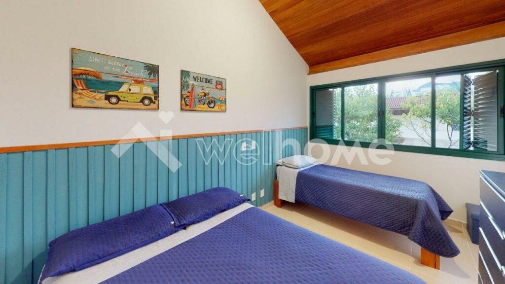 Quarto da Casa em Condomínio na Praia em São Sebastião, um dos airbnb em Barra do Una. Uma cama de casal e uma de solteiro têm uma comoda entre si na parede oposta. Ao lado direito da cama de solteiro há uma janela aberta.