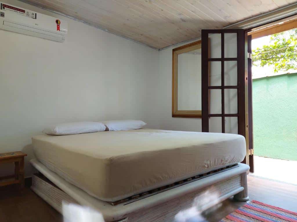Foto do quarto no Residencial Marina Del Sol. Representa o post sobre airbnb em Paúba. No centro há uma cama de casal box. Na direita há uma porta para o quintal. No canto esquerdo ao lado da cama, há uma mesa pequena de cabeceira.