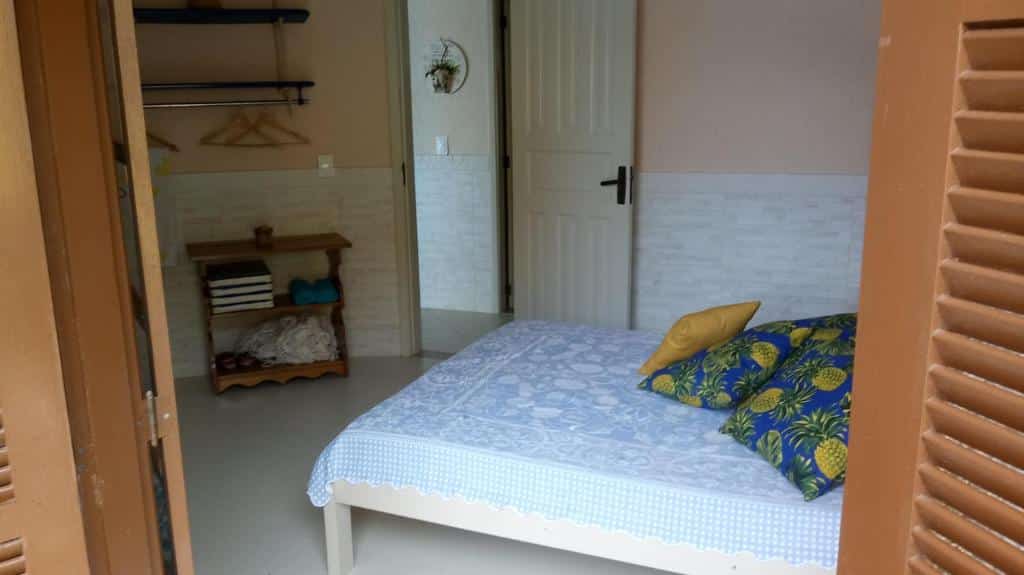 Quarto da Casa da Praia Pé na Areia. Uma cama de casal do lado direito, do lado esquerdo cabideiro e uma cômoda.