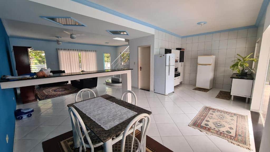 Cozinha da Casa de praia na Mococa com mesa de mármore com quatro cadeiras do lado esquerdo da imagem, do lado direito duas geladeiras e armário. Representa airbnb na praia de Tabatinga