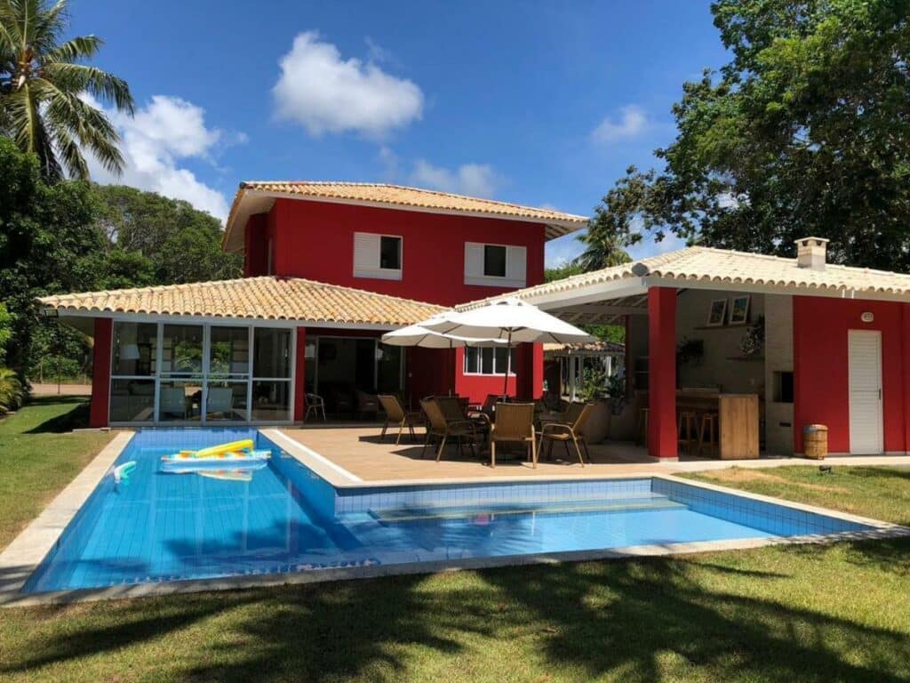 Frente da Casa Complexo Costa do Sauípe durante o dia com piscina a frente e ao fundo a propriedade.