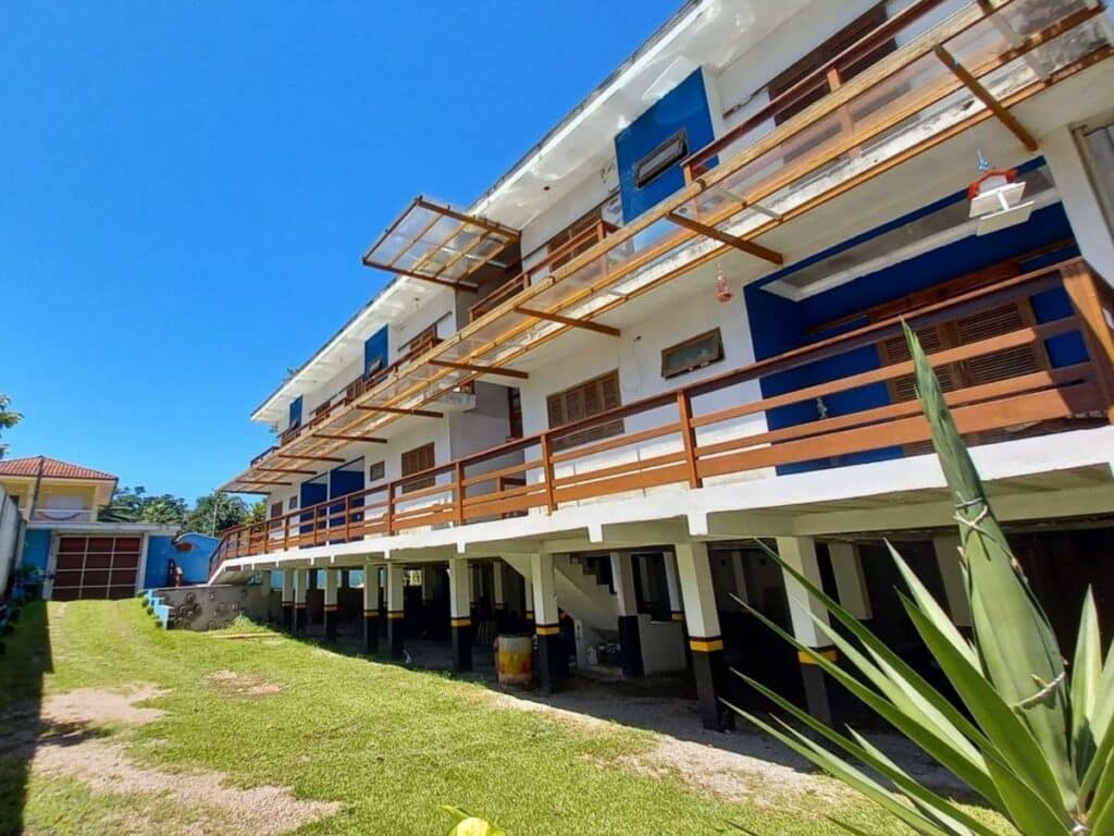 Frente da Waimea FLATS Itamambuca durante o dia do lado direito da imagem o edifico com vários apartamentos. Representa airbnb na praia do Félix.