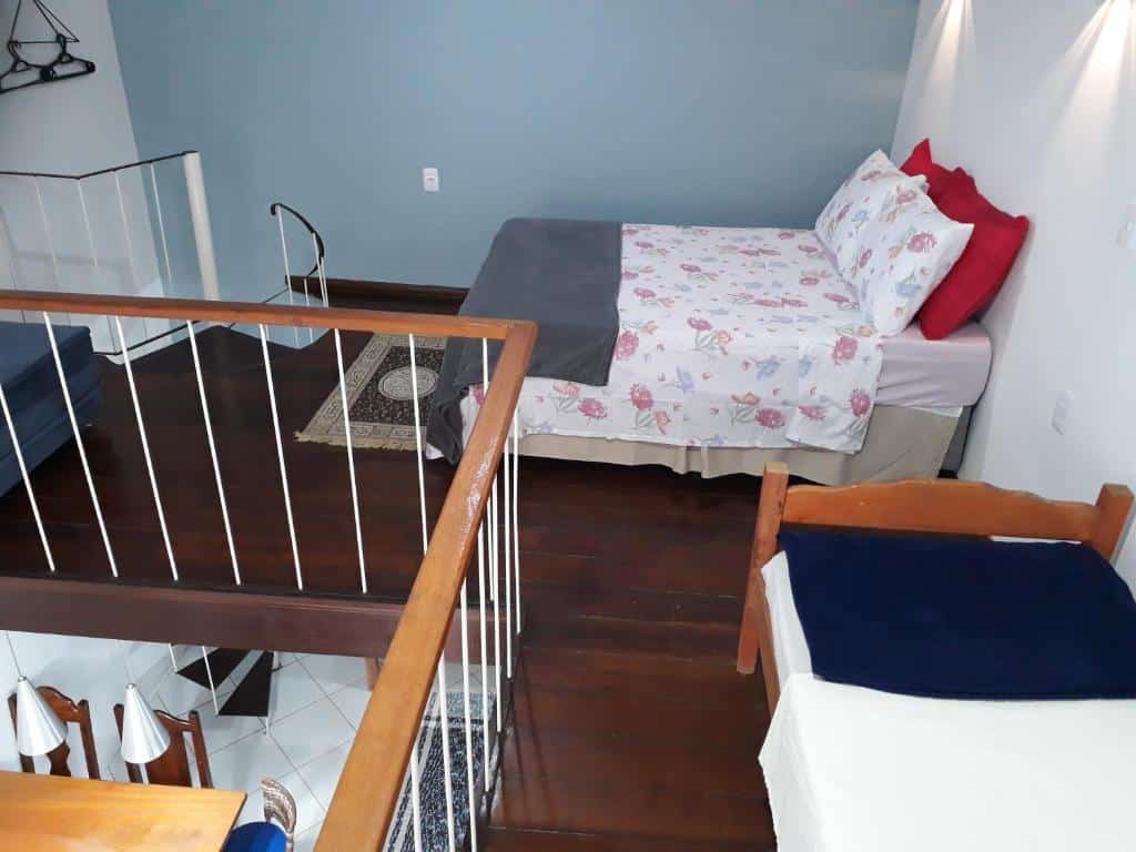 Quarto do airbnb Loft e Vila da Praia Studios Ilha Grande. No canto esquerdo está a escada que dá acesso ao primeiro andar, no canto direito há uma cama de casal e na frente há outra cama, porém de solteiro. Imagem para ilustrar o post airbnb em Ilha Grande.