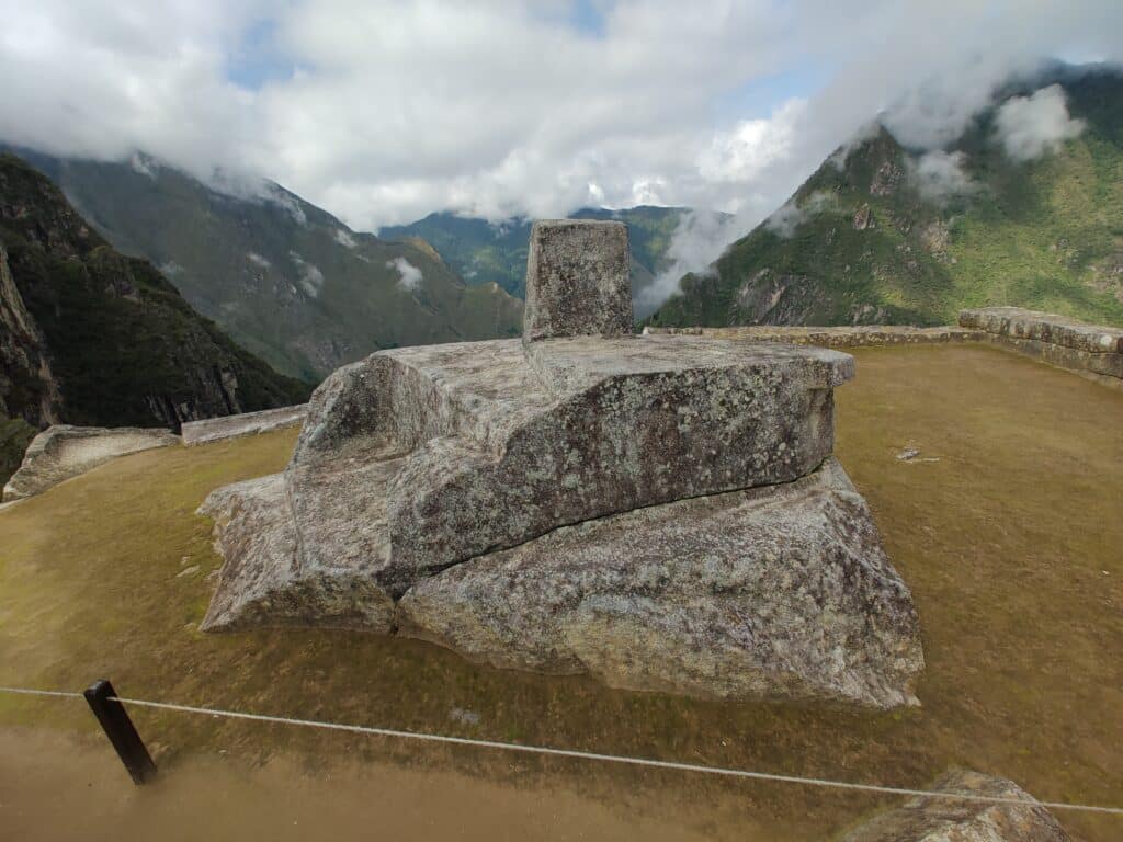 duas grandes pedras esculpidas em cima uma da outra, com uma pequena pedra sobre as duas para representar o ponteiro do relógio solar usado pelos povos incas em machu picchu